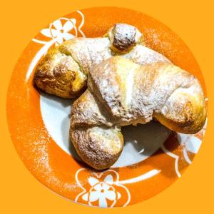 un plato con dos donuts en un plato naranja en Bed and Breakfast Arcobaleno, en Casteltermini