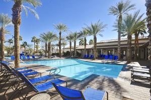 een zwembad met blauwe stoelen en palmbomen bij H90 Single Story Townhome Near Beautiful Fountain Condo in La Quinta