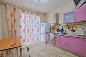 トムスクにあるАпартаменты Советская 98のピンクのキャビネットとテーブル付きのキッチン