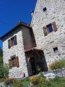 un gran edificio de piedra con ventanas y flores en la parte delantera en Chez Claire en Latouille-Lentillac
