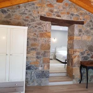 a bedroom with a stone wall with a bed and a desk at Posada las Albarcas in La Cavada