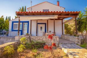 una pequeña casa blanca con pérgola de madera en Holiday house with sea view and private garden, en Samos