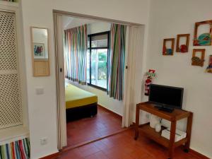 a room with a bedroom with a bed and a television at Studio Pedras d'el Rei in Santa Luzia