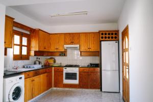 a kitchen with wooden cabinets and a white refrigerator at Malietzis House in Pano Arodes