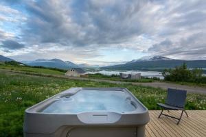 uma banheira de hidromassagem sentada num deque ao lado de uma cadeira em Viking Cottages & Apartments em Akureyri