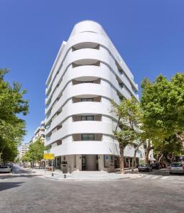 Hotel Lima - Adults Recommended في مربلة: مبنى أبيض على شارع المدينة به أشجار