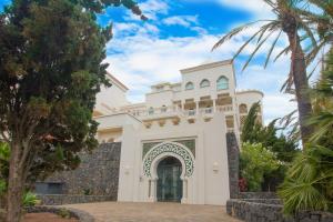 a white house with a gate and palm trees at Apartamento Vista Lotos in Puerto de la Cruz
