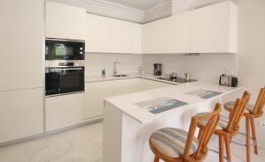 a kitchen with white cabinets and a counter with chairs at Apartamento Vista Lotos in Puerto de la Cruz