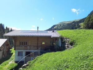 una casa su una collina in un campo verde di Apartment Linders Vorsass - Alphütte by Interhome a Rougemont