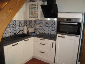 een keuken met witte kasten en een zwarte magnetron bij Holiday Home Hühnerhaus by Interhome in Nonnevitz