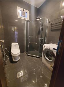 a bathroom with a toilet and a washing machine at Passion Hotel Villas in Khamis Mushayt