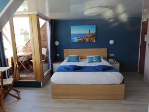 a bedroom with a bed with a blue wall at Hotel De La Mer in Trégastel