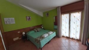 a green bedroom with a bed and a window at Orso Momo in Calizzano