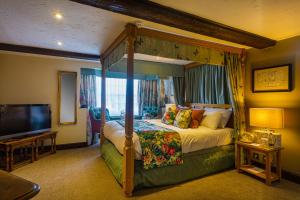 a bedroom with a canopy bed and a television at The Bell Inn, Stilton, Cambridgeshire - The Coaching Inn Group in Peterborough +56 photos