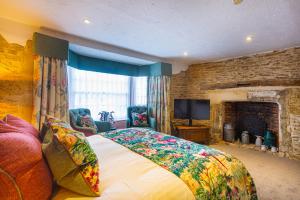 a bedroom with a large bed and a fireplace at The Bell Inn, Stilton, Cambridgeshire - The Coaching Inn Group in Peterborough