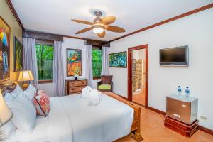 a bedroom with a white bed and a ceiling fan at Hotel Casa Roland Golfito Resort in Golfito