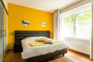 Un dormitorio con una cama con paredes amarillas y una ventana en Fred&Breakfast, en Gante