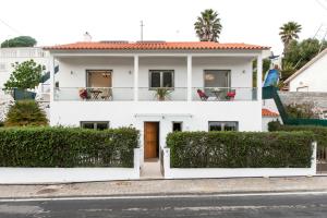a white house with chairs on a balcony at Beachouse - Surf, Bed & Breakfast in Ericeira