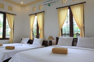 three beds in a room with windows at Dewa House Bisma in Ubud