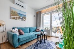 un soggiorno con divano blu e una grande finestra di Symphony Baltica Towers Aparthotel a Danzica