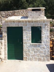 a stone building with a green door and two windows at Apartman Nina in Makarska