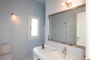 a white bathroom with a sink and a mirror at Villa Nireas in Platis Yialos Mykonos