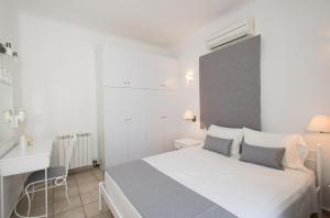 Biała sypialnia z białym łóżkiem i biurkiem w obiekcie Villa Nireas w mieście Platis Gialos Mykonos