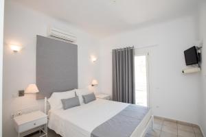 a white bedroom with a large bed and a window at Villa Nireas in Platis Yialos Mykonos