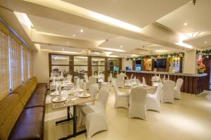 a dining room with white tables and white chairs at Fersal Hotel - Puerto Princesa in Puerto Princesa City