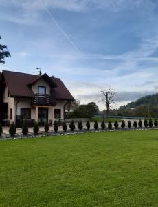 una casa con un césped verde delante de ella en Domek w górach, en Sucha Beskidzka