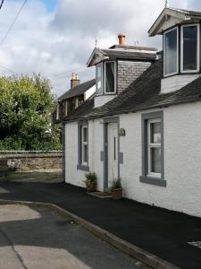 a white house with a driveway in front of it at RoSE COTTAGE THREE BEDROOM HOUSE WITH PARKING in Carsphairn