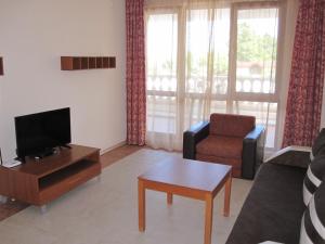 a living room with a couch and a tv and a chair at Byala Palace Apartments in Byala
