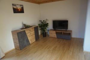 sala de estar con TV de pantalla plana y centro de entretenimiento de madera en Berghaus Alberta, en Michelsberg