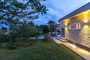 a brick house with lights on the side of it at Villa Viktoria poll&garden view in Kaštelir