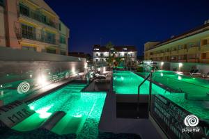 una piscina por la noche con luces verdes en Apartamentos Turísticos Playa Mar I en Montalvo