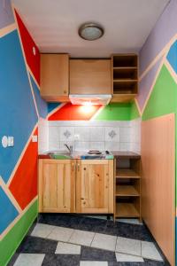 una pequeña cocina con paredes coloridas y armarios de madera. en Bled Hostel en Bled