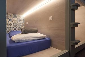 a small room with a blue bed with a pillow at Vert Lodge Chamonix in Chamonix-Mont-Blanc