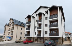 an apartment building with cars parked in a parking lot at Apartman Libra Zlatibor in Zlatibor
