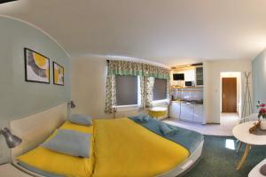 1 dormitorio con 1 cama amarilla y cocina en Penzion Mini, en Liberec