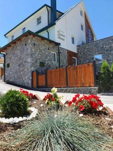 a building with a fence and flowers in front of it at Dream House Hotel & Spa in Kolašin