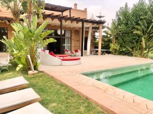 un patio trasero con piscina y una casa en Villas Fleurs Marrakech, en Marrakech