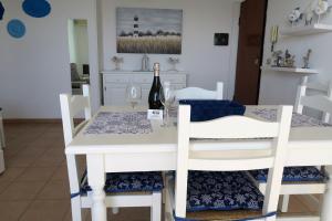 ein Esszimmer mit einem weißen Tisch und 2 Flaschen Wein in der Unterkunft Appartamenti Sole in Alghero