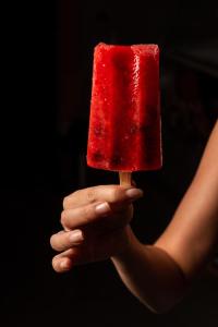 une personne tenant un morceau de crème glacée rouge sur un bâton dans l'établissement Villa Gelso, à Vesime