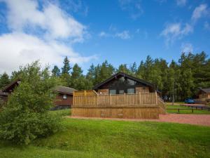 a large wooden cabin with a deck on a grass field at Pine Tree in Newcastle upon Tyne
