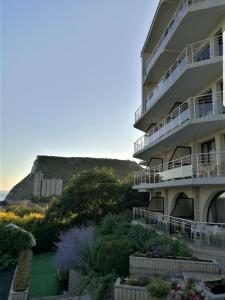 a building with a garden and a hill in the background at Family Hotel Venera in Kavarna