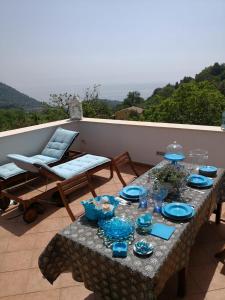 un tavolo con piatti e bicchieri blu su un balcone di Il carrubo B&b a Maratea