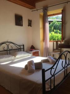 a bedroom with a bed with white sheets and a window at Country traditional house in Corfu village, Greece in Sinarádes