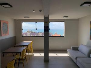a living room with a couch and tables and a window at Liiv Cobogó - Natal Ponta Negra in Natal