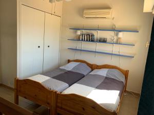Schlafzimmer mit einem Holzbett mit blauen Regalen in der Unterkunft Duplex rénové les pieds dans l'eau in Calvi