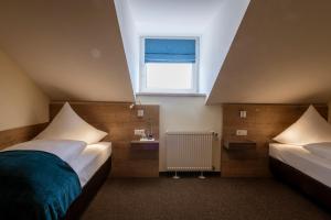 een slaapkamer op zolder met 2 bedden en een raam bij Gasthof Hotel Drei Tannen Altdorf in Altdorf